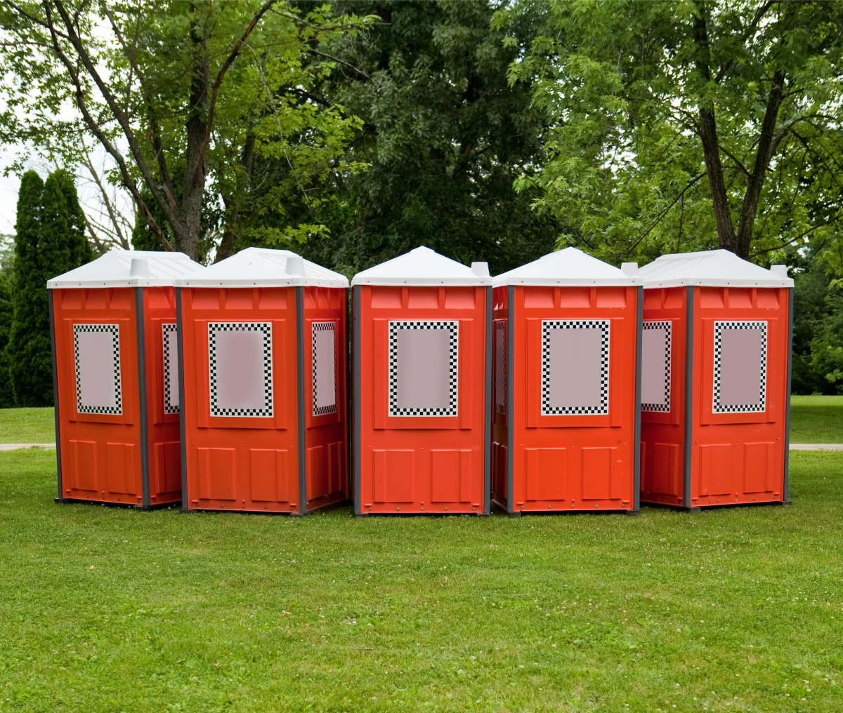 Red portable toilets on grass